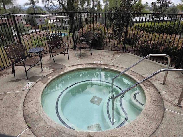 view of swimming pool featuring fence and a community hot tub
