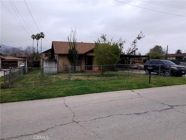 view of front of home featuring stucco siding, driveway, a gate, a front lawn, and a fenced front yard