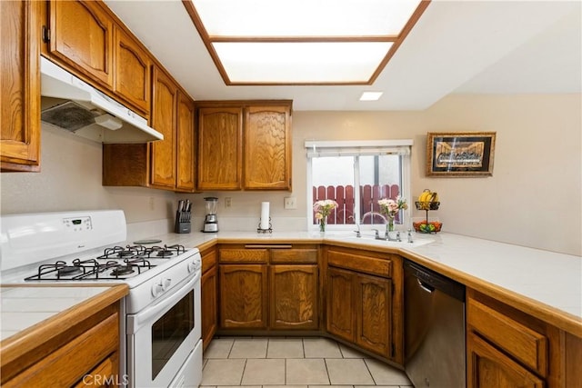 kitchen featuring a sink, under cabinet range hood, gas range gas stove, stainless steel dishwasher, and tile countertops