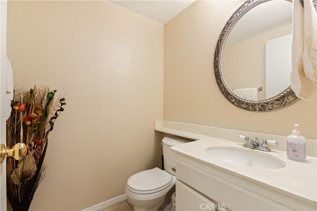 bathroom featuring toilet, vanity, and baseboards