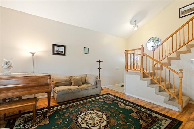 living area with stairway, baseboards, wood finished floors, and vaulted ceiling