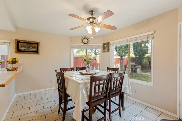 dining space featuring light tile patterned floors, a ceiling fan, and baseboards