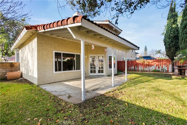 rear view of property with fence, a yard, stucco siding, french doors, and a patio area