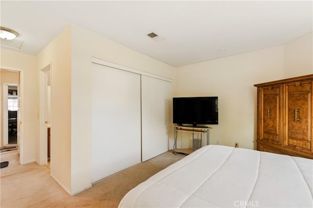 bedroom with visible vents, a closet, and light carpet