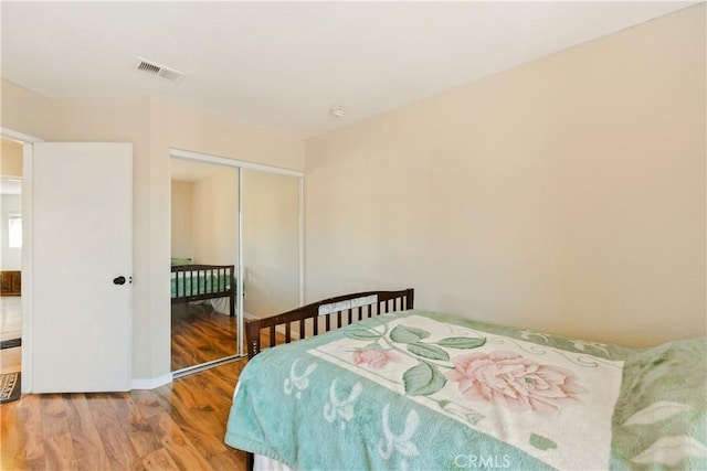 bedroom featuring a closet, visible vents, and wood finished floors