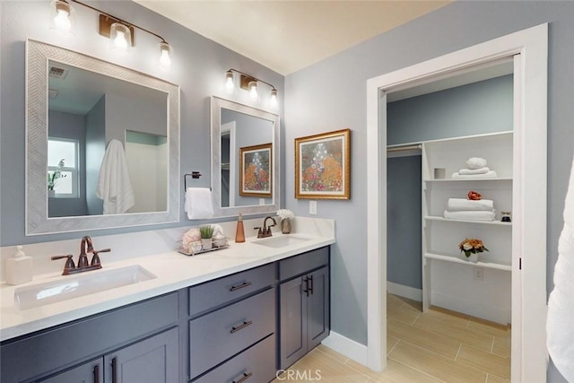 full bathroom with double vanity, wood finish floors, baseboards, and a sink