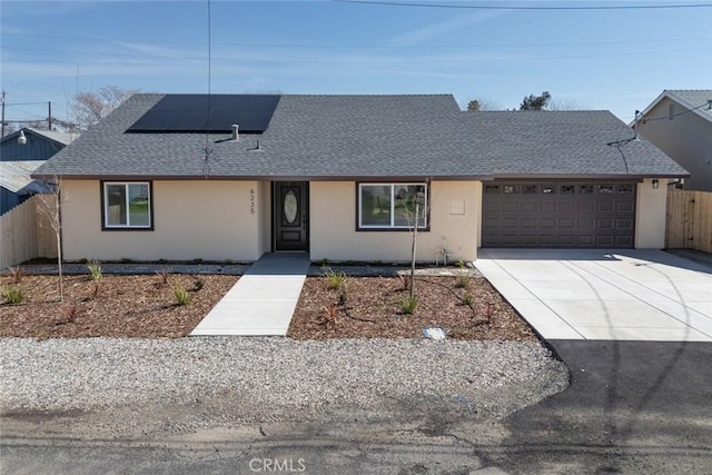 ranch-style house featuring an attached garage, fence, roof with shingles, and stucco siding