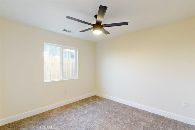 carpeted empty room featuring visible vents, a ceiling fan, and baseboards
