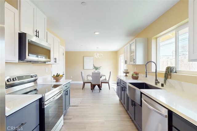 kitchen featuring light countertops, white cabinets, appliances with stainless steel finishes, and a sink