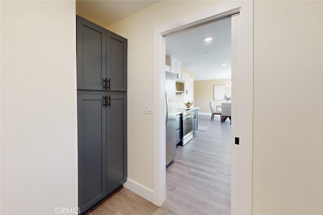 hallway featuring light wood finished floors and baseboards