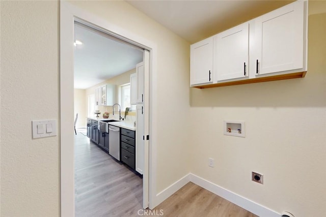 laundry area with electric dryer hookup, washer hookup, light wood-style flooring, cabinet space, and baseboards