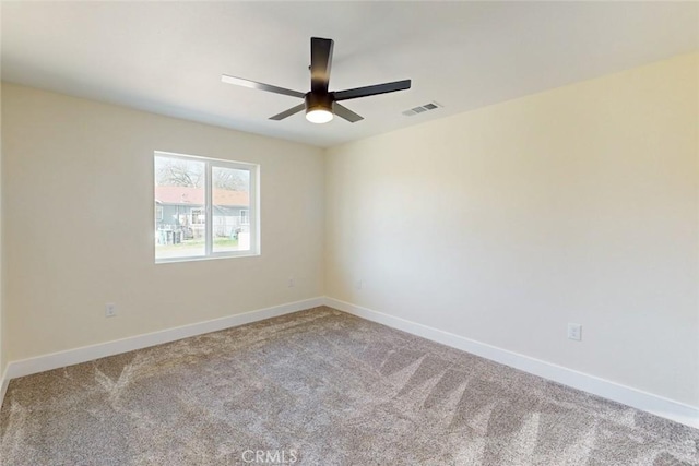 carpeted spare room featuring baseboards, visible vents, and ceiling fan