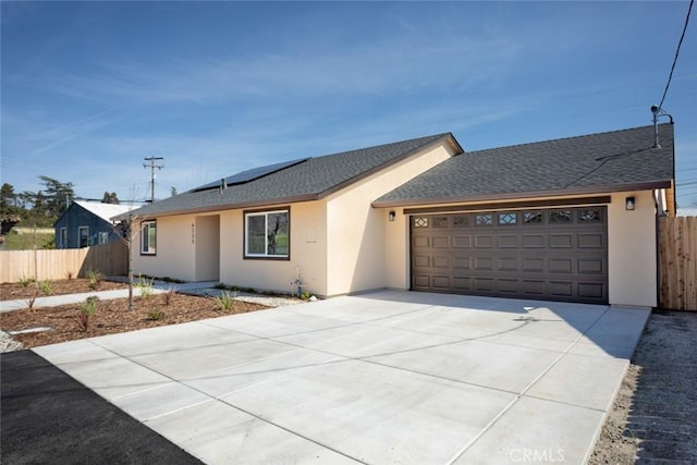 ranch-style home with fence, a garage, roof mounted solar panels, and stucco siding