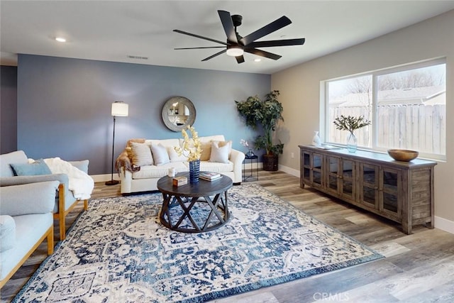 living room featuring a ceiling fan, wood finished floors, visible vents, baseboards, and recessed lighting