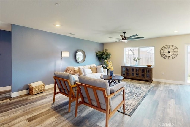 living area featuring baseboards, wood finished floors, and a ceiling fan