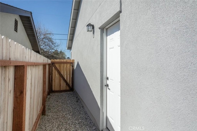 view of side of property with stucco siding and fence