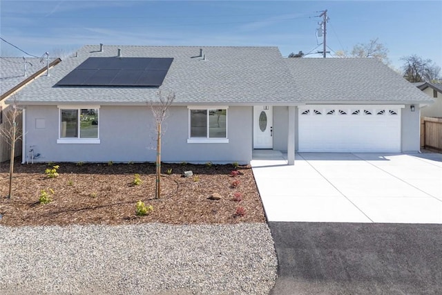 ranch-style home featuring solar panels, a shingled roof, concrete driveway, stucco siding, and a garage