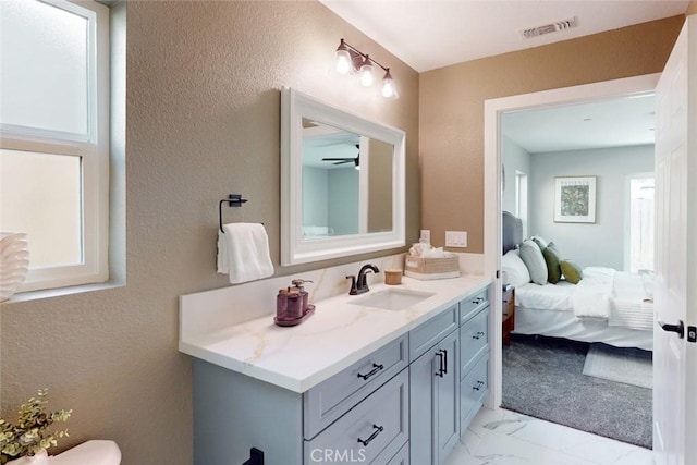 bathroom with visible vents, ensuite bathroom, a textured wall, marble finish floor, and vanity