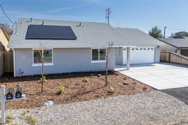 single story home featuring solar panels, a shingled roof, fence, concrete driveway, and a garage