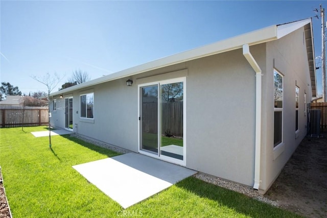 rear view of house with fence private yard, a lawn, cooling unit, and stucco siding