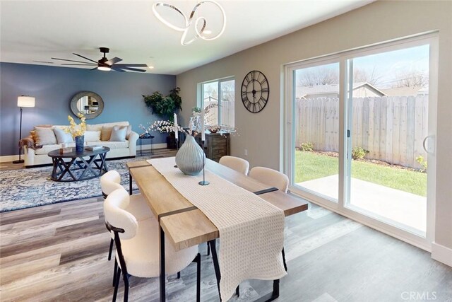 dining room featuring ceiling fan with notable chandelier, baseboards, and wood finished floors