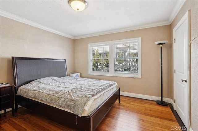 bedroom featuring baseboards, ornamental molding, and wood finished floors