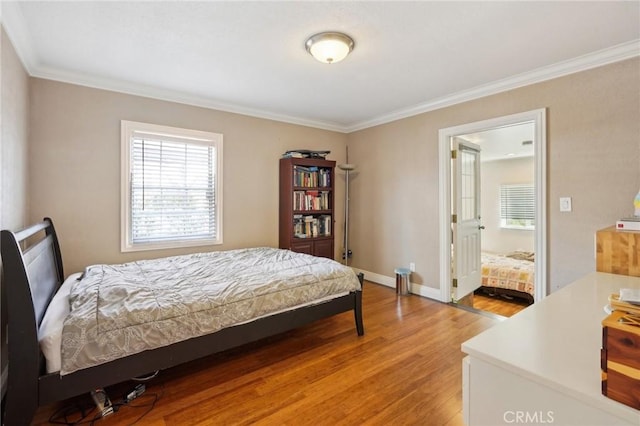 bedroom with baseboards, crown molding, and light wood-style flooring