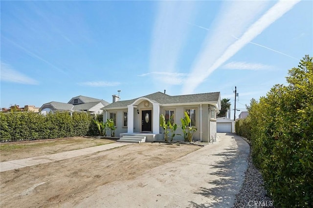 bungalow-style house with stucco siding, an outdoor structure, and a garage
