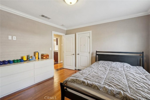 bedroom with visible vents, ornamental molding, and wood finished floors