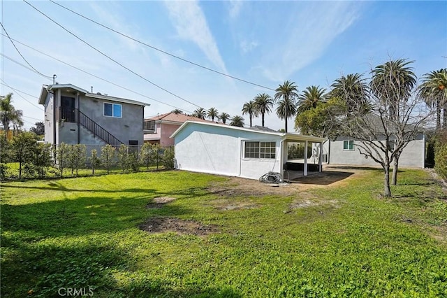 back of house featuring stucco siding, a lawn, and fence