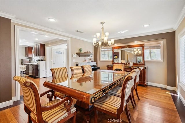 dining room with visible vents, crown molding, baseboards, a chandelier, and light wood-type flooring