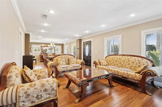 living area with light wood finished floors, visible vents, a healthy amount of sunlight, and crown molding