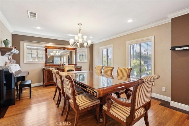 dining area featuring light wood-type flooring, visible vents, an inviting chandelier, and ornamental molding