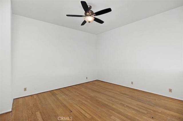 empty room featuring baseboards, a ceiling fan, and light wood-style floors