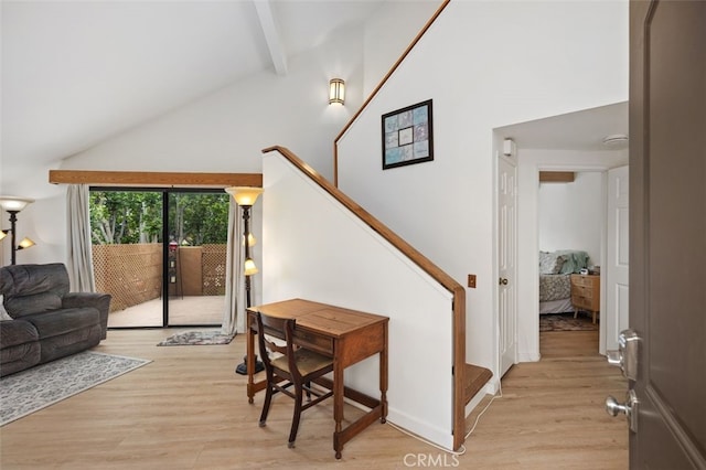 living area with beamed ceiling, high vaulted ceiling, stairs, and light wood finished floors