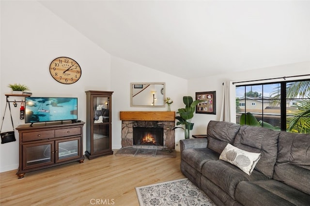 living room featuring light wood finished floors, a fireplace, and lofted ceiling