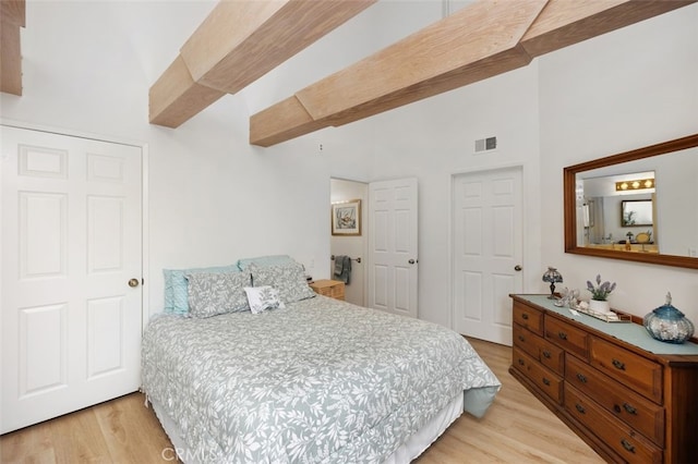 bedroom with beam ceiling, visible vents, and light wood-type flooring