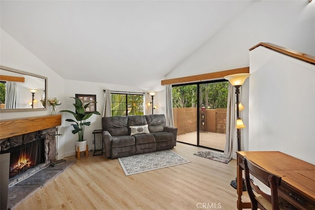 living room featuring a stone fireplace, wood finished floors, and vaulted ceiling