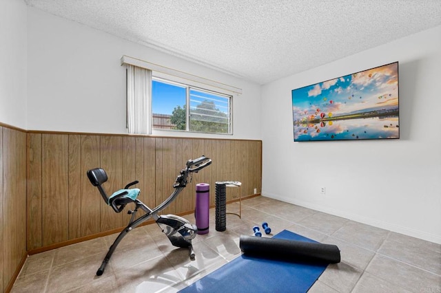 exercise room with wooden walls, wainscoting, and a textured ceiling