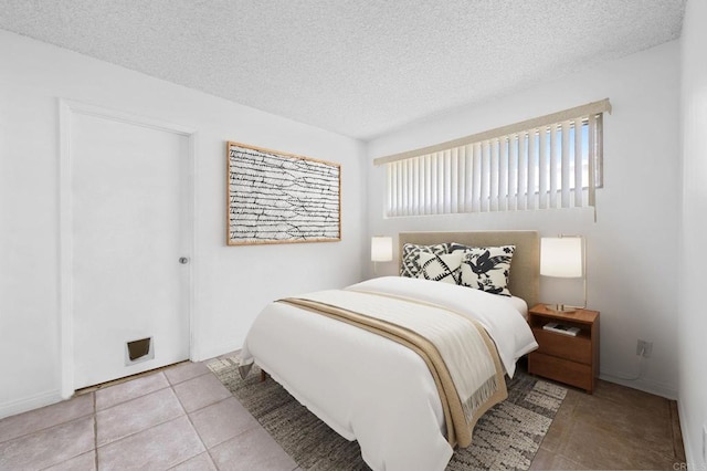 bedroom with tile patterned floors, baseboards, and a textured ceiling