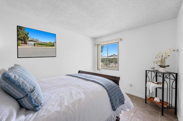 bedroom with tile patterned floors, baseboards, and a textured ceiling