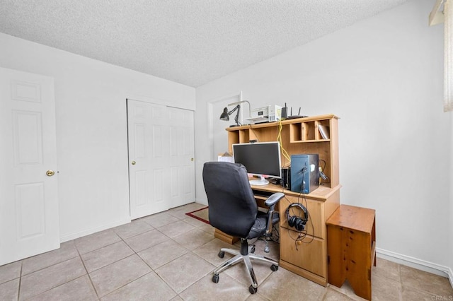 tiled office space with a textured ceiling and baseboards