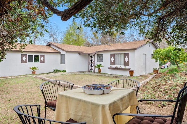 back of property featuring a yard and stucco siding