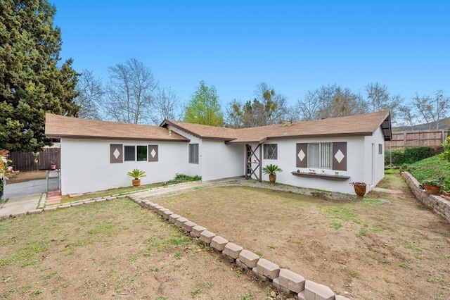 single story home with stucco siding, a front lawn, and fence