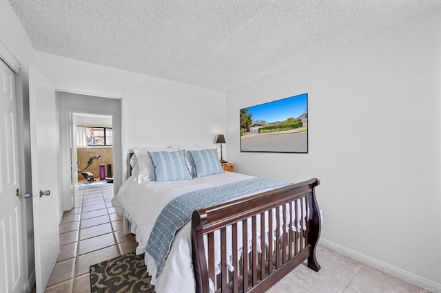 bedroom featuring tile patterned floors, baseboards, and a textured ceiling