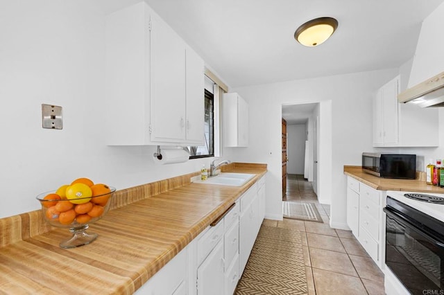 kitchen with custom exhaust hood, a sink, white cabinets, range with electric stovetop, and stainless steel microwave