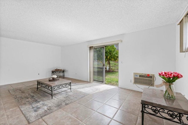 unfurnished living room featuring a wall mounted air conditioner, baseboards, and a textured ceiling