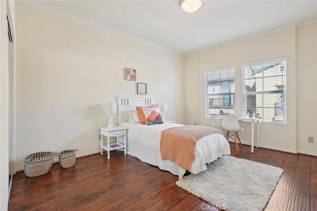 bedroom with baseboards, wood-type flooring, and crown molding