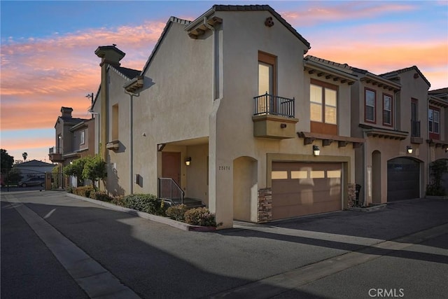 view of front facade with a balcony, a residential view, stucco siding, and a garage