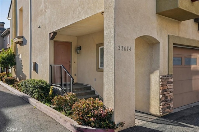 entrance to property featuring a garage and stucco siding